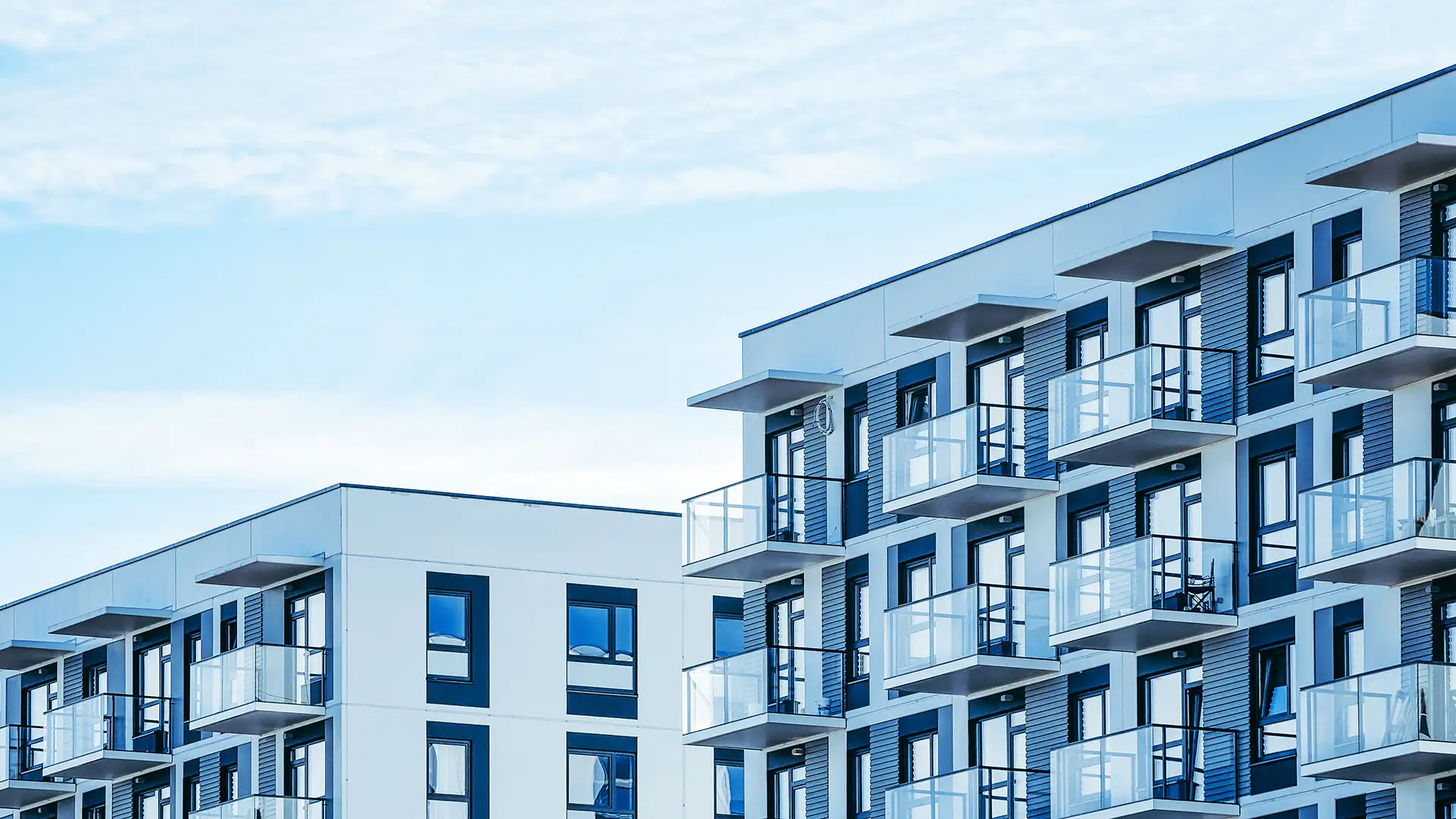 Modernes Mehrfamilienhaus bei strahlend blauen Himmel.