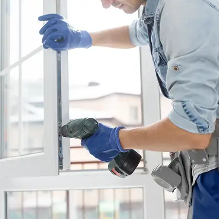 Ein Mann arbeitet mit einem Akkuschrauber an einem Fenster.